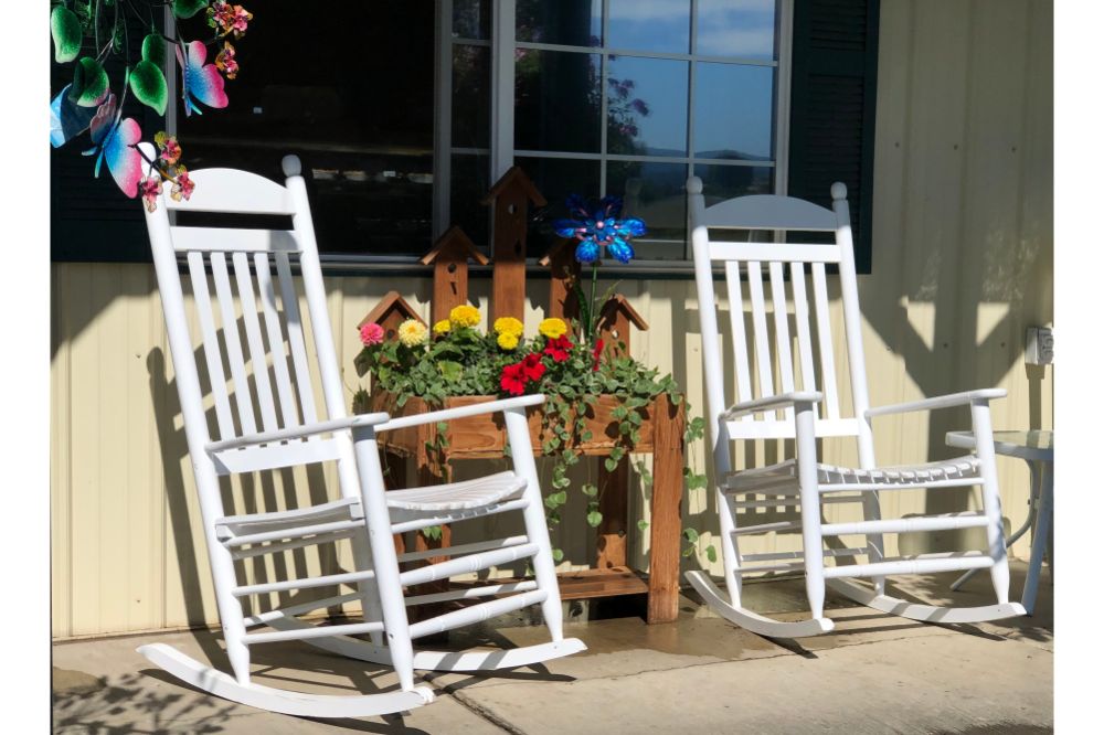 country style front porch seating with white rocking chairs and fresh flowers